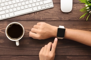 Picture of arm wearing smart watch for measuring fitness activity. Image also shows a coffee cup and keyboard